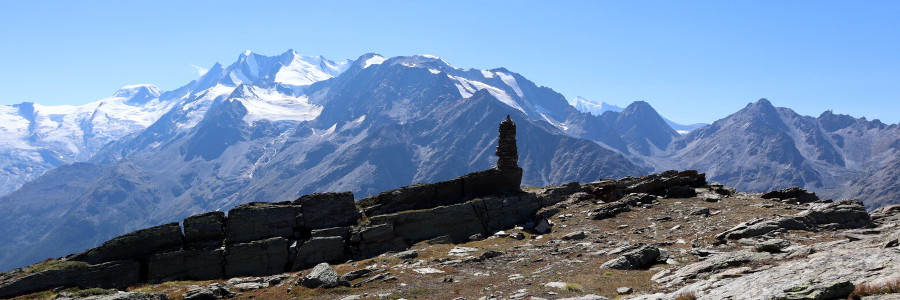 Kamienny obelisk Sattel na tle najwyższych w okolicy: Domu i Täschhornu